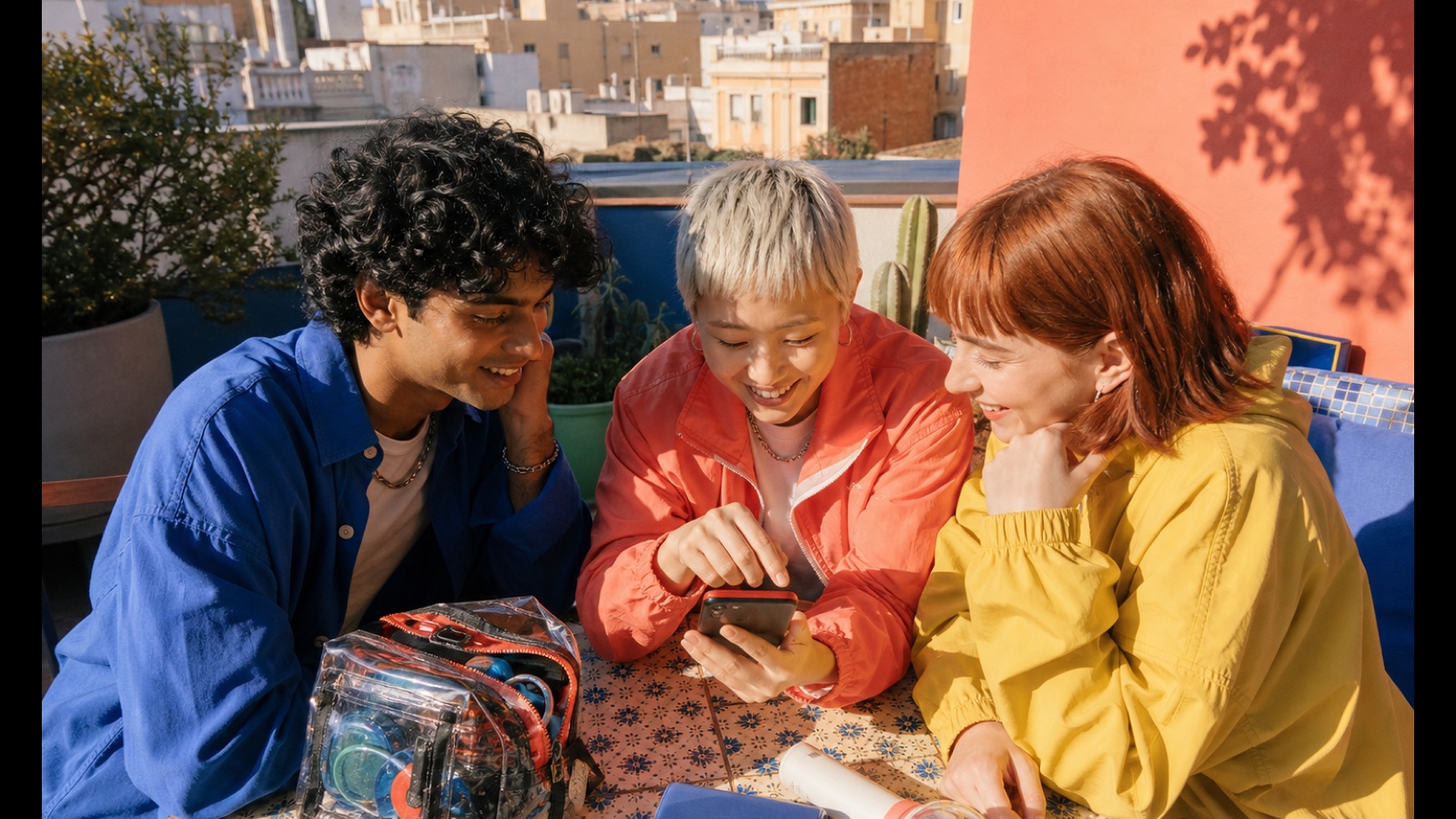 AI-generated editorial scene of three friends preparing for a K-pop concert on a sunny Barcelona rooftop.